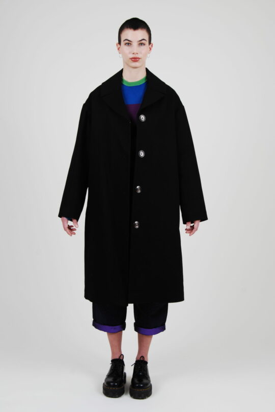 Le mannequin porte le long manteau Chloé conçu en coton upcycling éco-responsable